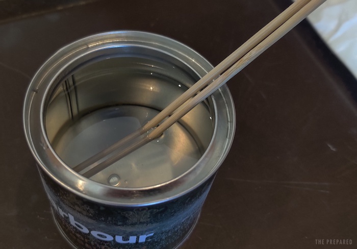 A can of melted wax with a pair of chopsticks inside